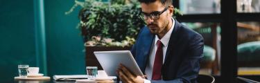 رجل يرتدي بدلة جالسًا على كرسي باستخدام لوح