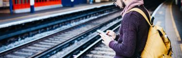 Man checking his mobile phone waiting for a train
