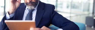Senior man wearing glasses looking at his tablet