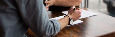 Man writing on paper next to a man with animated hands