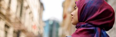 امرأة ترتدي الحجاب الأحمر والأزرق تسير في الشارع