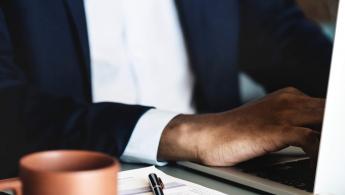 Corporate banking man typing on his keyboard with a cup of coffee