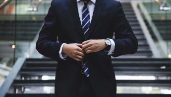 Man in a smart suit adjusting tie