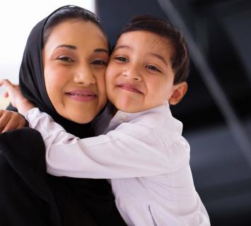 سيدة مبتسمة ترتدي الحجاب وتعانق ابنها